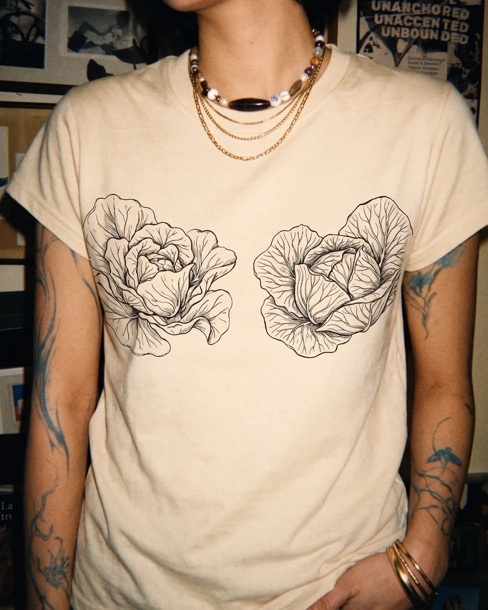 A natural cream tee printed in black line work with two heads of butter lettuce, drawn leaf by leaf and placed like a bra